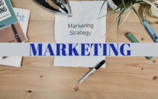 A desk with a piece of paper with the words Marketing Strategy typed on it with a band across the desk saying marketing